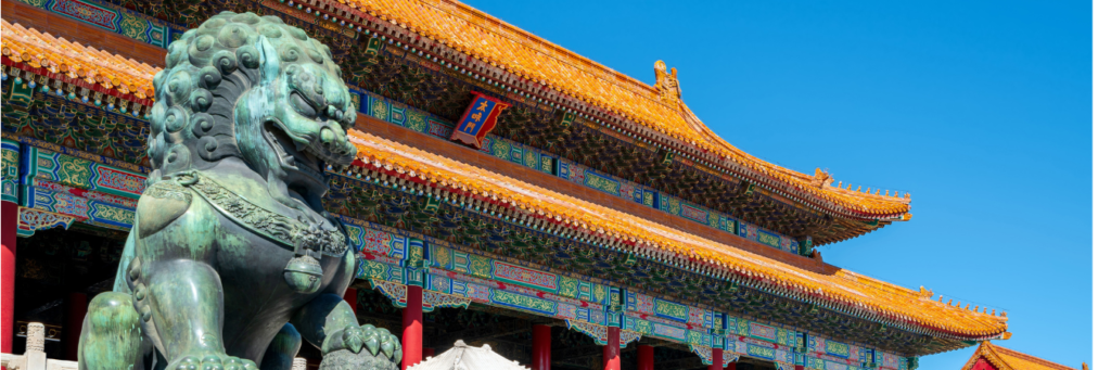 León guardián de bronce en la Ciudad Prohibida, Beijing, China, con techos dorados tradicionales